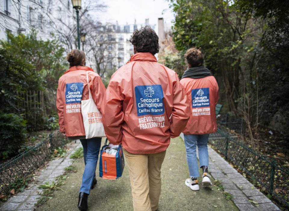 Jeunes bénévoles de dos portant la veste du Secours Catholique